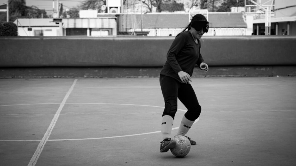 Una jugadora de fútbol para ciegas controla la pelota con el pie derecho.