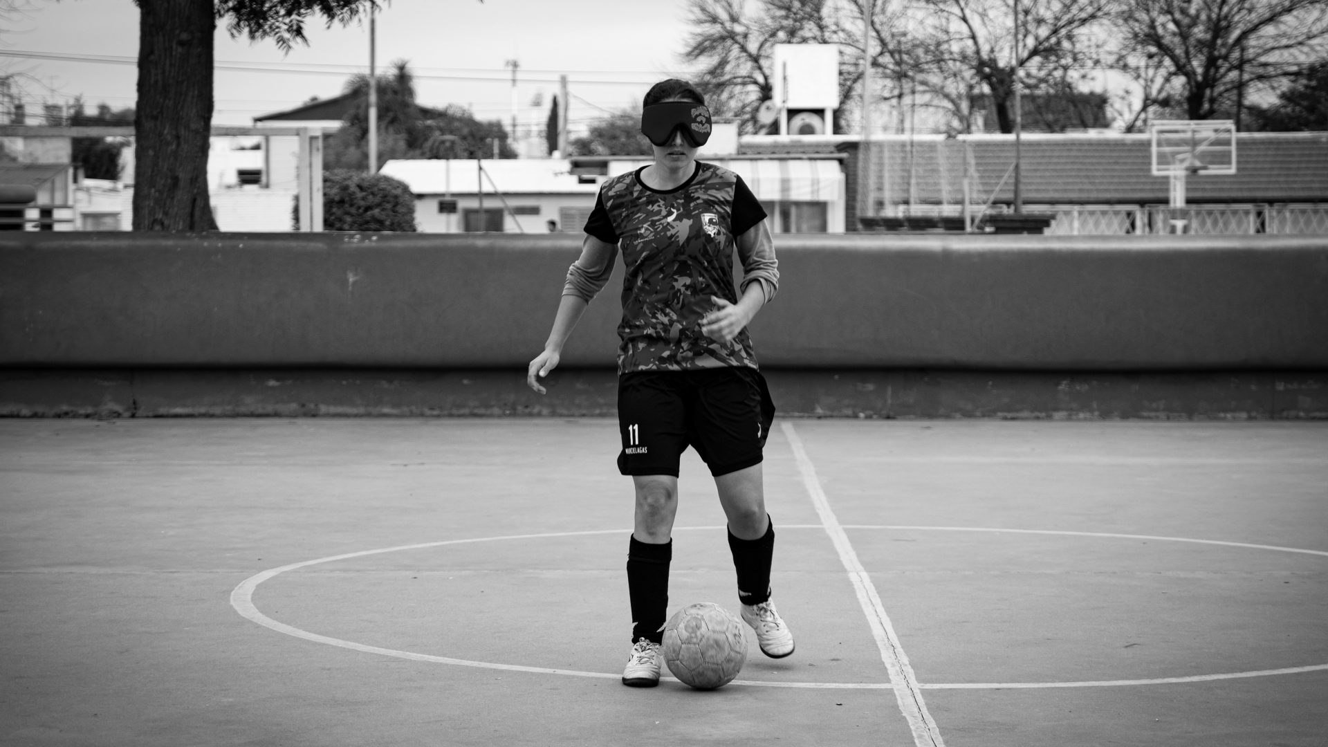 Una jugadora de fútbol para ciegas en el centro de la cancha, con la pelota en los pies.